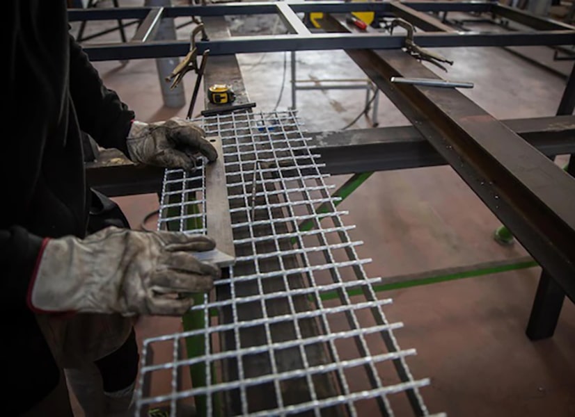 Operaio misura grata poggiata su assi di ferro